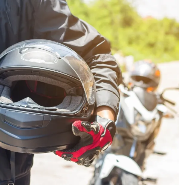 Motorcycle driver holding their helmet. Our motorcycle accident lawyers fight for those injured in a crash on a motorcycle in the Bryna and College Station areas.