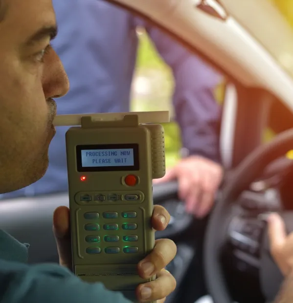A man breathing into a breathalyzer after being pulled over for drunk driving. A car accident caused by someone driving drunk could cause tragedy for you or a loved one. If you've been in an accident our personal injury lawyer for College Station and Bryan, TX can help.