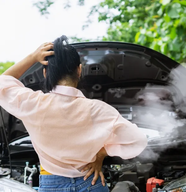 woman looking at the engine of a car over heating.