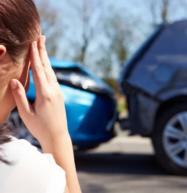 woman with her head in her hand looking at a car accident.