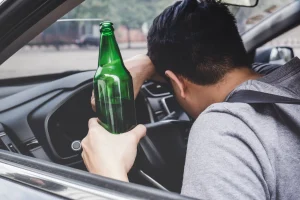 An inebriated driver with their head on the steering wheel after hitting another car.