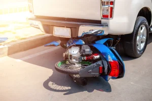 A motorcycle under a truck after being hit and the driver was taken to the hospital. The rider may need to make a claim for their emotional distress.