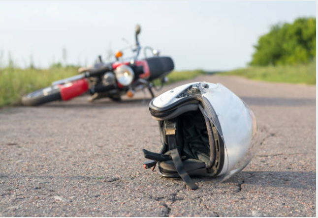 A motorcycle laying in the road with a helmet.