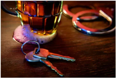 A drink on a bar with handcuffs and keys.